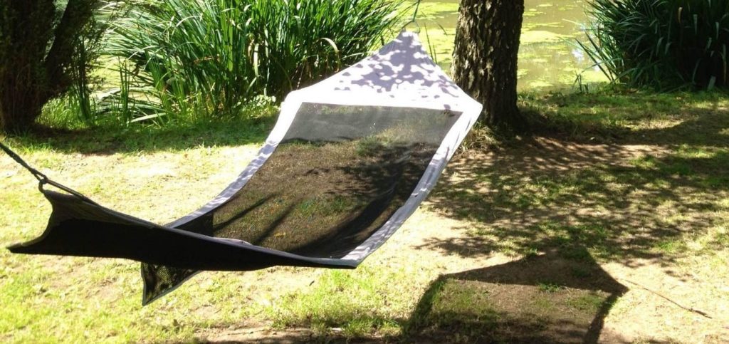 A hammock gently swaying in the shade beneath a large, leafy tree.